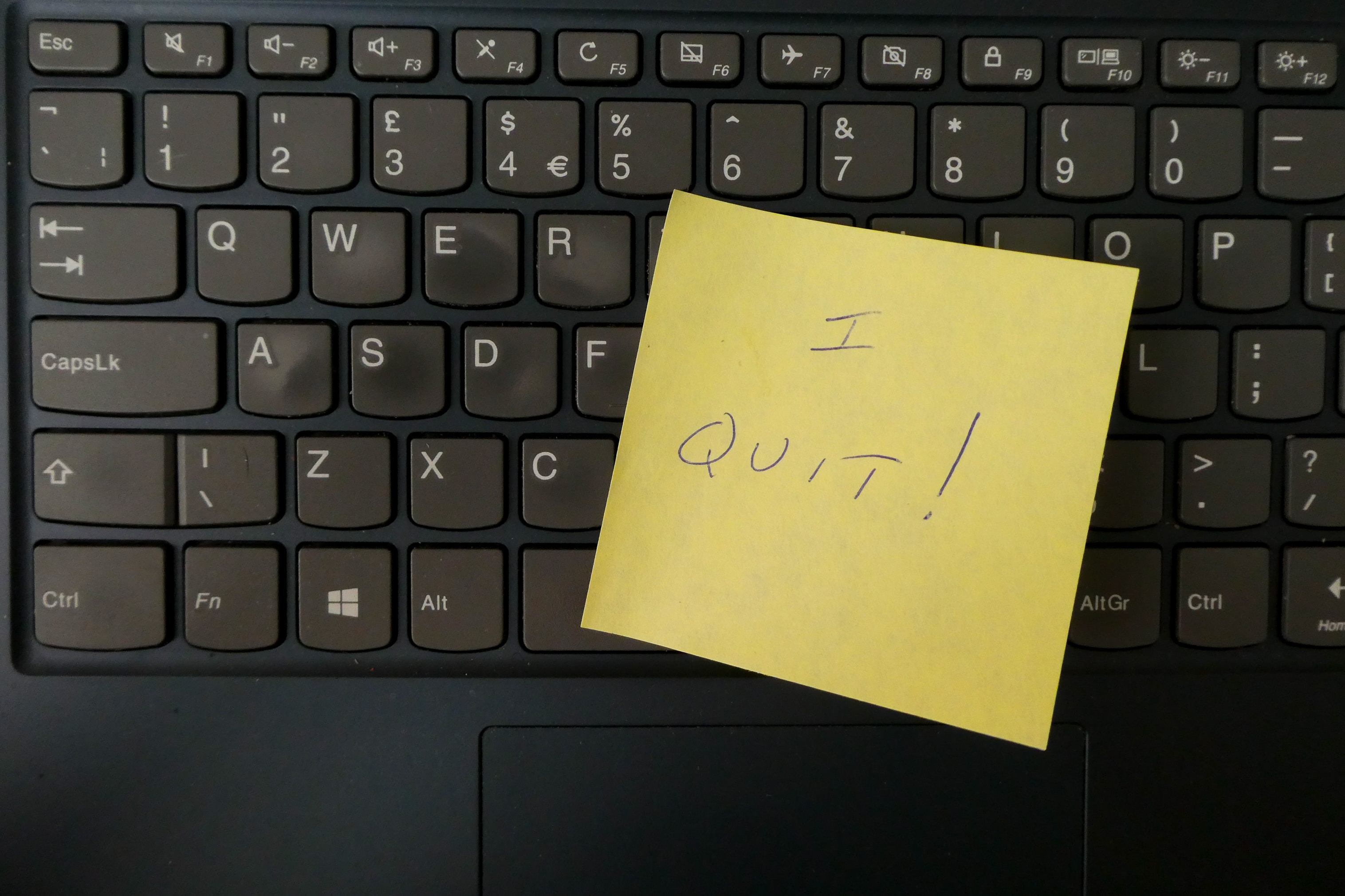 An image of a sticky note with "I quit" written on it, stuck on a keyboard